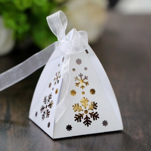 Detail van piramide kerstsnoepdoos met holle sneeuwvlok en wit zijden lint
