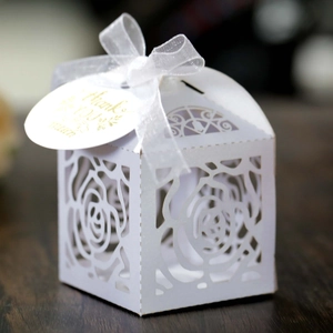Detail of white laser-cut rose candy box with silk ribbon and gold Thank You tag
