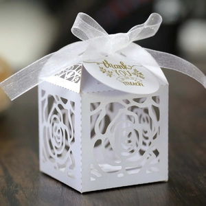 Detailed laser-cut rose pattern on white paper wedding favor box with ribbon