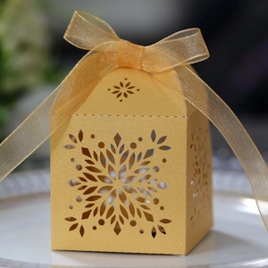 Macro shot of gold laser-cut snowflake gift box with an elegant chiffon ribbon bow