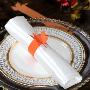 Close-up of orange maple leaf paper napkin ring on a white plate for autumn table decor