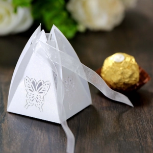 Detailed laser-cut white butterfly candy box with silk ribbon on wooden surface
