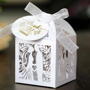 Macro of white laser-cut wedding favor box with pearl coating and Thank You tag