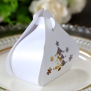 Detail view of white triangular gift box with hollow Christmas tree and snowflake patterns