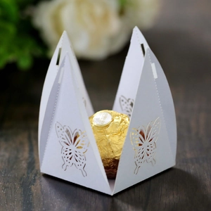 Macro shot of white laser-cut butterfly candy box with a chocolate inside for weddings