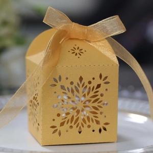 Detailed laser-cut snowflake patterns on a ginger gold gift box with a sheer organza ribbon