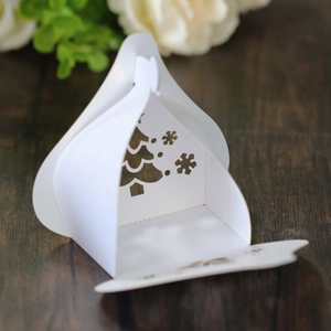 Close-up of white paper candy box with hollow-out Christmas tree and snowflake details