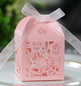 Macro shot of laser-cut rose hollow favor box in pink cardstock with white ribbon bow