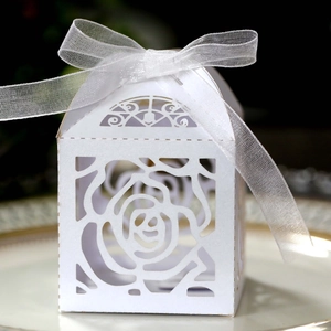Close-up of white laser-cut rose wedding candy box with a delicate organza ribbon bow