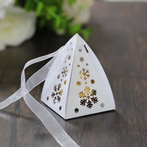Gedetailleerde weergave van witte piramide geschenkdoos met gouden sneeuwvlokken en een lint