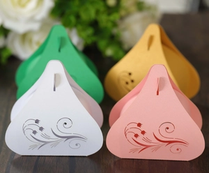 Laser-cut tulip wedding favor boxes in four colors on a wooden surface with white roses