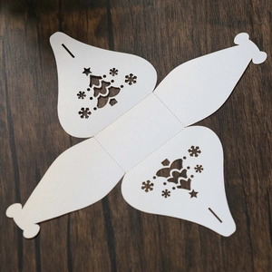 Flat lay of laser-cut white Christmas tree and snowflake hollow candy box template