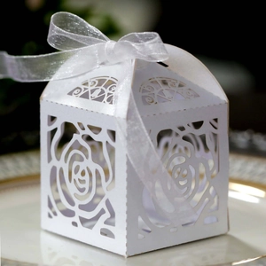 Close-up of laser-cut white rose gift box with organza ribbon on elegant plate