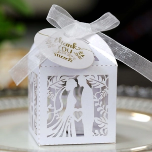 Close-up of laser-cut white wedding favor box with ribbon and gold Thank You tag