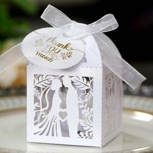 Close-up of laser-cut wedding favor box with bride and groom silhouette and silk ribbon