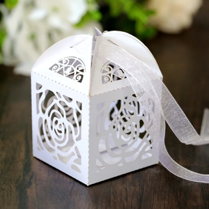 Detail of white laser-cut candy box with rose patterns and ribbon for wedding gift