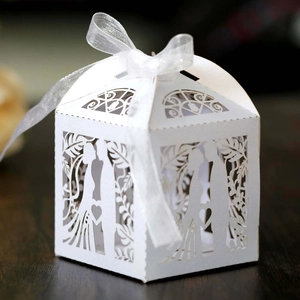 Detail of laser-cut white wedding favor box with bride and groom silhouette and ribbon