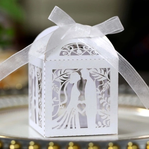 Macro shot of laser-cut wedding favor box with bride and groom silhouette and satin ribbon