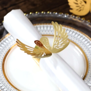 Close-up of golden swan napkin ring with laser-cut hollow details on a white napkin