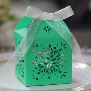 Detail of laser-cut snowflake hollow gift box in green with a white satin ribbon bow