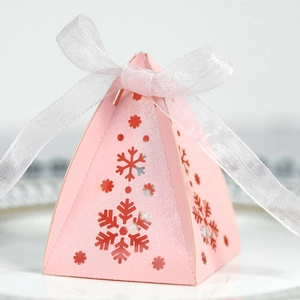 Detail van roze piramide geschenkdoos met holle sneeuwvlokpatronen en wit organza lintje