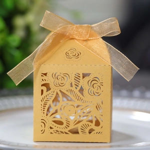 Golden laser-cut rose hollow candy box with translucent ribbon on white porcelain plate