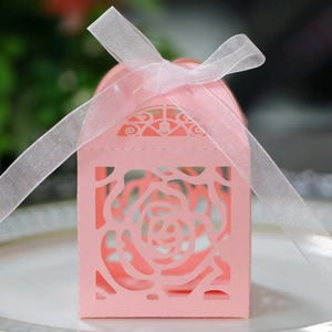 Close-up of pink laser-cut candy box with rose patterns and white ribbon bow