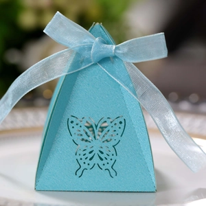 Macro detail of a light blue pyramid candy box with laser-cut butterfly and silk ribbon