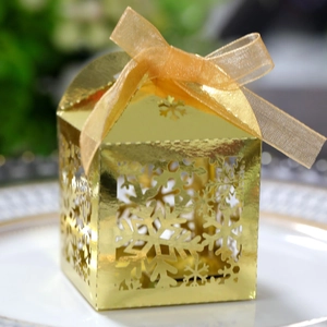 Détail de la boîte cadeau dorée avec flocon de neige ajouré et ruban élégant