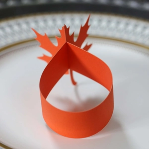 Orange maple leaf paper napkin ring set on a white decorative plate for autumn decor