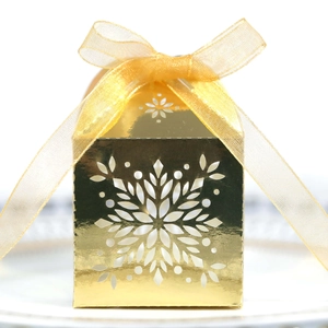 Detail of golden Christmas snowflake laser-cut gift box with festive ribbon bow