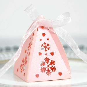 Detail van roze piramide geschenkdoos met laser-gesneden sneeuwvlok en lint