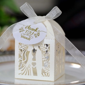 Macro view of white laser-cut wedding favor box with elegant lace silhouette and ribbon