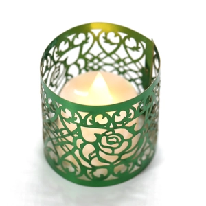 Dettaglio di portacandele in metallo verde intagliato al laser con rose e luce a LED