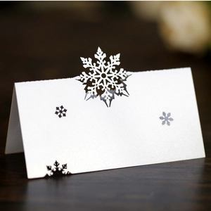 Close-up of white laser-cut snowflake place cards on a dark wooden table background