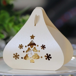 Macro shot of cream Christmas pyramid box with hollowed tree and snowflake patterns