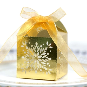 Macro shot of golden snowflake cutout candy box with a matching organza ribbon bow