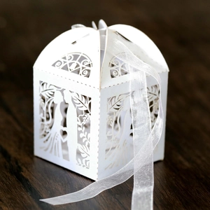 Detailed laser-cut heart pattern on white wedding favor box with ribbon detail