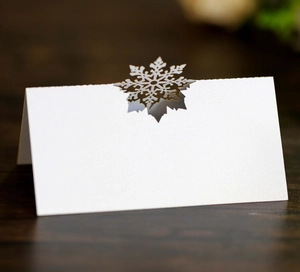 Macro shot of laser-cut gold snowflake on white pearlescent paper wedding place card
