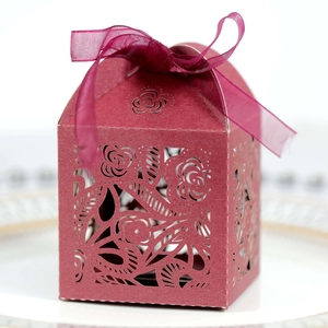 Close-up of laser-cut hollow rose pattern on burgundy gift box with silk ribbon