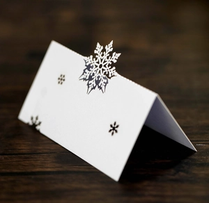 Laser-cut white snowflake place card on wooden table for wedding and banquet events