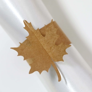 Detail of laser cut kraft paper maple leaf napkin ring with veins on white cloth