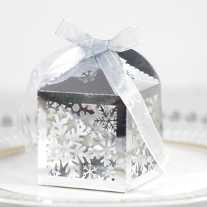 Détail de la boîte à bonbons argentée ajourée de flocons avec ruban bleu clair