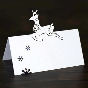 Macro detail of laser-cut white card with reindeer and snowflake patterns on wood