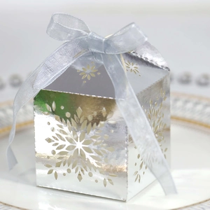 Silver snowflake cutout candy box with light blue ribbon on white plate