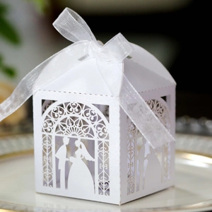 Macro detail of laser-cut wedding candy box with bride and groom silhouette and ribbon