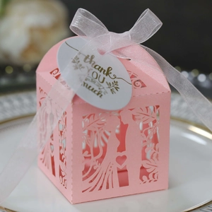 Detail of pink laser-cut wedding candy box with bride and groom silhouette and ribbon