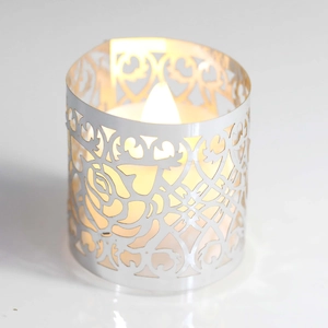 Dettaglio del portacandele in metallo bianco tagliato al laser con rose e luce LED calda
