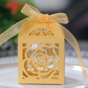 Close-up of golden hollow candy box with rose pattern and semi-transparent organza ribbon
