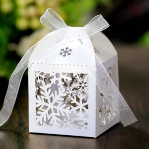 Close-up of white snowflake cutout gift box with elegant organza ribbon and pearl finish
